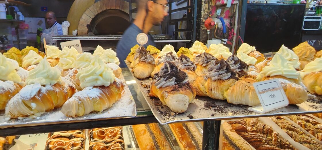 Assorted pastries topped with cream and chocolate in a bakery display.