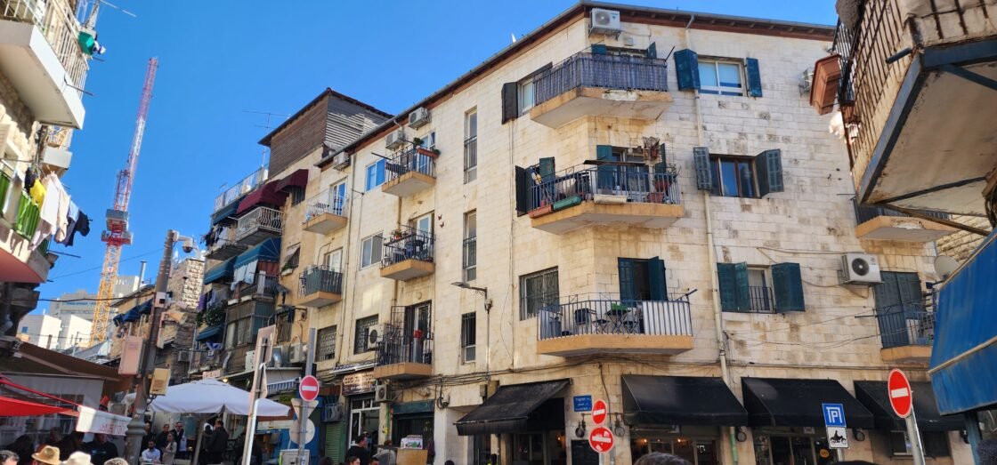Street view of apartment buildings with balconies under a clear blue sky.